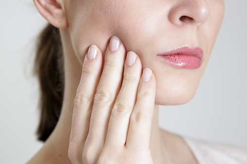 Person holding their hand to their painful jaw.