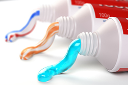 close up of 3 different tubes of toothpaste in different colors