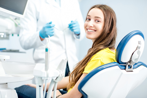 A young woman smiling after a negative oral cancer screening