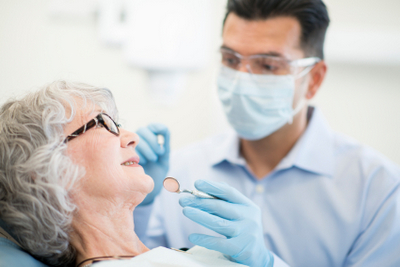 Dentist talking to his elderly female patient.