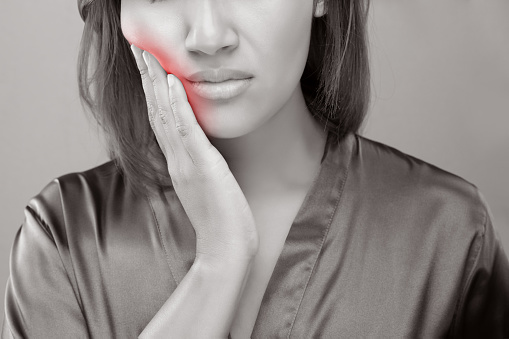 a woman holding her inflamed jaw